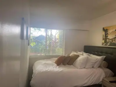 a bedroom with a white bed with a window at Quiet-comfy 3 bedroom house on a tree lined street in Kitsilano in Vancouver