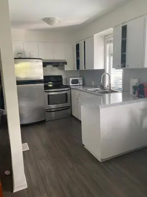 a kitchen with white cabinets and stainless steel appliances at Quiet-comfy 3 bedroom house on a tree lined street in Kitsilano in Vancouver