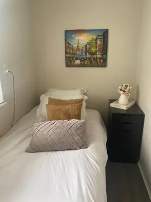 a bedroom with a white bed with a picture on the wall at Quiet-comfy 3 bedroom house on a tree lined street in Kitsilano in Vancouver