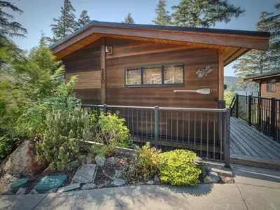a small cabin with a porch and a fence at Wickham's Wake - 3BR Oceanfront - pet friendly in Port Renfrew