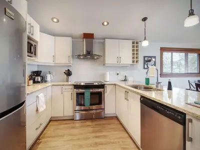 a kitchen with white cabinets and stainless steel appliances at Wickham's Wake - 3BR Oceanfront - pet friendly in Port Renfrew