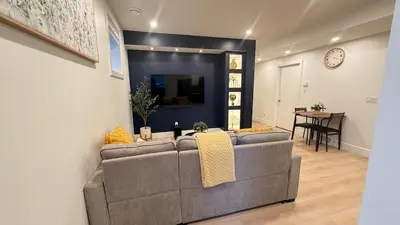 a living room with a gray couch and a tv at Modern 1BR Private Suite NW Near Airport & Amazing Shopping! Free Netflix, Parking! in Calgary