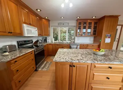 a kitchen with wooden cabinets and a granite counter top at Woodhaven - Entire Home, Ocean Front in Bowser