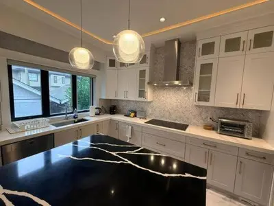 a large kitchen with white cabinets and a black floor at YVR3106 | Cozy 3BR in Central Vancouver | 15 min to Downtown in Vancouver