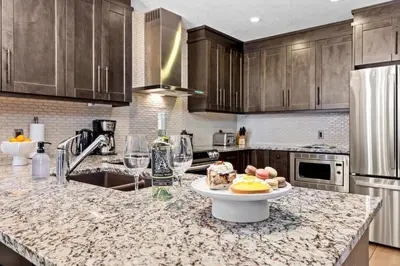 a kitchen counter with a plate of food and wine glasses at Stunning Penthouse with Mtn Views Hot Tub and Pool in Canmore