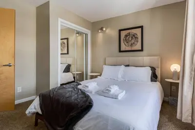 a bedroom with a large white bed with towels on it at Stylish Mountain View Condo with Gym in Canmore