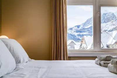 a bed with a window with a mountain view at Stylish Mountain View Condo with Gym in Canmore