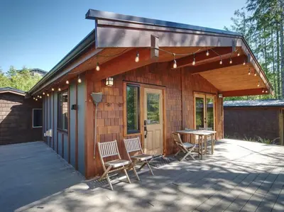 a house with chairs and a table in front of it at Explorer's Retreat Sauna & Bunkhouse & Fire pit in Port Renfrew