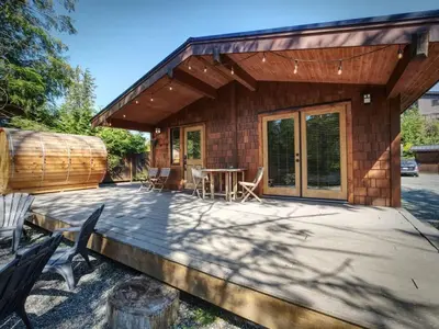 a house with a patio and a table and chairs at Explorer's Retreat Sauna & Bunkhouse & Fire pit in Port Renfrew