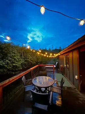 a table and chairs on a deck at night at Hot Tub - Large Fully Enclosed deck - Pet Friendly in Port Renfrew