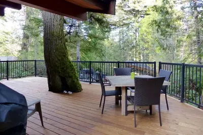 a table and chairs on a deck with a tree at Hot tub Oasis Among Trees - Pet Friendly in Port Renfrew