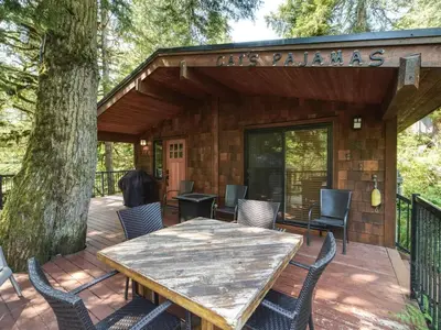 a patio with a wooden table and chairs and a building at Hot tub Oasis Among Trees - Pet Friendly in Port Renfrew