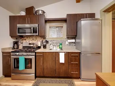 a kitchen with stainless steel appliances and wooden cabinets at Hot tub Oasis Among Trees - Pet Friendly in Port Renfrew