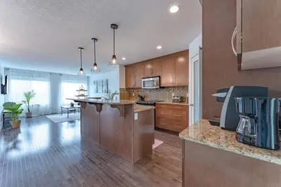 a large kitchen with wooden cabinets and a kitchen island at Cozy Large Family Home near Lake, AC, Full Kitchen in Calgary