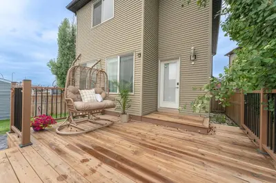 a rocking chair on a wooden deck next to a house at Cozy Large Family Home near Lake, AC, Full Kitchen in Calgary