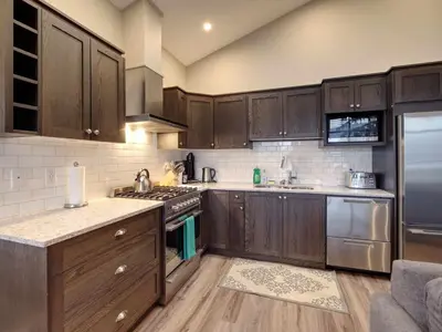 a kitchen with wooden cabinets and stainless steel appliances at Amazing Marina & Oceanfront View - Pet Friendly - Sleeps 6 in Port Renfrew