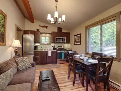 a living room and kitchen with a table and a couch at Hot Tub - Pet Friendly - Cozy Escape with Fire Pit in Port Renfrew