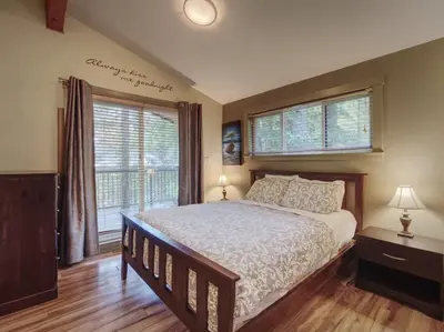 a bedroom with a large bed and two windows at Hot Tub - Pet Friendly - Cozy Escape with Fire Pit in Port Renfrew