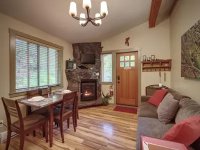 a living room with a couch and a table and a fireplace at French Girl's Lair - Pet Friendly - Garden View in Port Renfrew