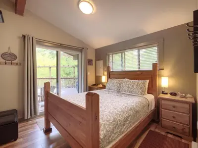 a bedroom with a bed and a large window at French Girl's Lair - Pet Friendly - Garden View in Port Renfrew