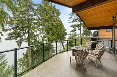 a balcony with a table and chairs and a view of the water at Seaside Haven -Hot Tub with Oceanfront View in Port Renfrew