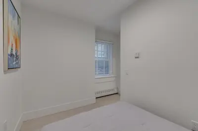 an empty white room with a window and a white rug at Spacious Apartment Fully Equipped in Prime Location in Vancouver