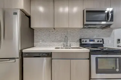 a kitchen with a sink and a microwave and a refrigerator at Spacious Apartment Fully Equipped in Prime Location in Vancouver