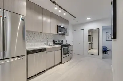 a kitchen with stainless steel appliances and white cabinets at Spacious Apartment Fully Equipped in Prime Location in Vancouver