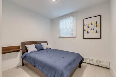 a bedroom with a bed with a blue comforter and a window at Spacious Apartment Fully Equipped in Prime Location in Vancouver
