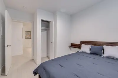 a white bedroom with a bed with blue pillows at Spacious Apartment Fully Equipped in Prime Location in Vancouver