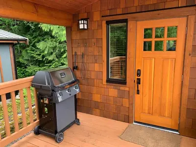 a grill on the front porch of a house at Enclosed deck - Hot tub - Pet Friendly- gas stove in Port Renfrew
