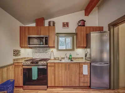 a kitchen with wooden cabinets and a stainless steel refrigerator at Enclosed deck - Hot tub - Pet Friendly- gas stove in Port Renfrew