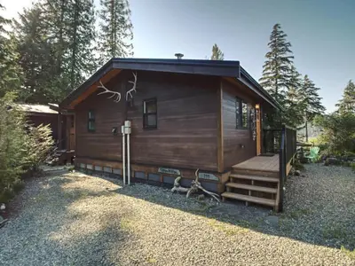 a log cabin with a porch and stairs to it at Tiltin Hilton- Ocean View - Pet Friendly - sleep 4 in Port Renfrew