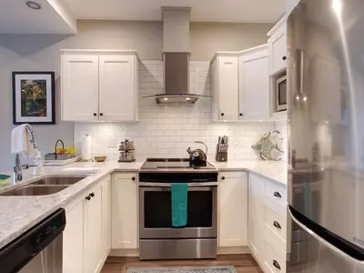 a kitchen with white cabinets and stainless steel appliances at Oceanfront Relaxing & Stunning View - Pet Friendly in Port Renfrew