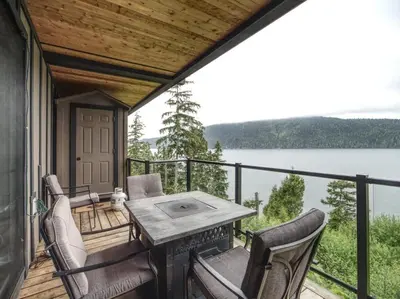 a porch with a table and chairs and a view of a lake at Oceanfront Relaxing & Stunning View - Pet Friendly in Port Renfrew