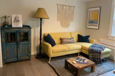 a living room with a yellow couch and a table at Beautiful Oasis in prime Vancouver BC with 2 bed and patio PLUS Studio available in Vancouver