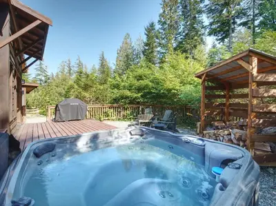 a hot tub in a backyard with a wooden deck at A slice of paradise with Hot Tub - Pet Friendly in Port Renfrew