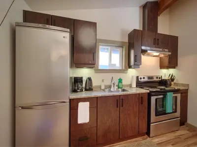 a kitchen with a stainless steel refrigerator and wooden cabinets at A slice of paradise with Hot Tub - Pet Friendly in Port Renfrew
