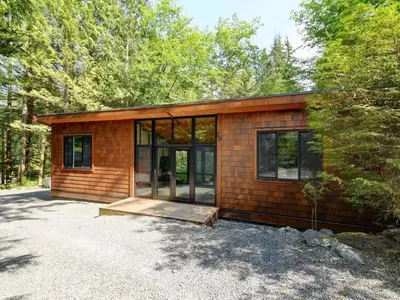 a small cabin in the woods with glass windows at Private treed setting - no pets - garden view in Port Renfrew