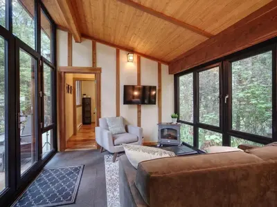 a living room with a couch and chairs and windows at Private treed setting - no pets - garden view in Port Renfrew