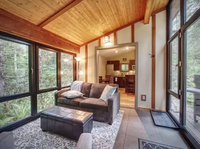 a living room with a couch and a table at Private treed setting - no pets - garden view in Port Renfrew