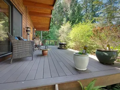 a deck with chairs and a grill on a house at Quiet Romantic Getaway - Non Pet Friendly in Port Renfrew