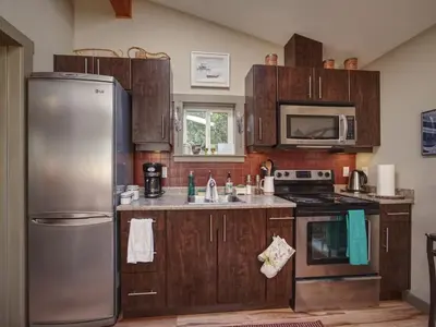 a kitchen with wooden cabinets and a stainless steel refrigerator at Quiet Romantic Getaway - Non Pet Friendly in Port Renfrew