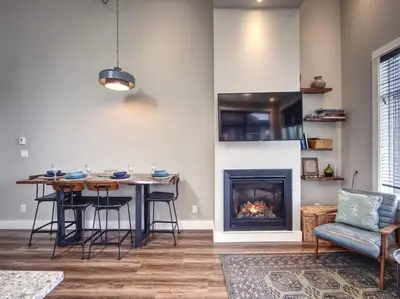 a living room with a table and a fireplace at Oceanfront Marina & Mountain views- pet friendly in Port Renfrew