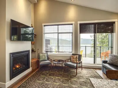 a living room with a fireplace and a couch and chairs at Oceanfront Marina & Mountain views- pet friendly in Port Renfrew