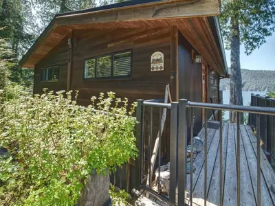 a cabin with a wooden deck and a fence at Oceanfront view 2 entertainment areas -Pet Friendly in Port Renfrew