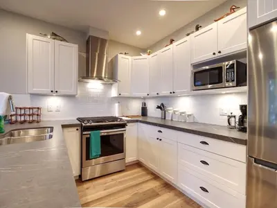 a kitchen with white cabinets and stainless steel appliances at The Salty Dog - Oceanfront Getaway - Great View - Pet Friendly in Port Renfrew