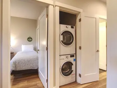 a bedroom with a washer and dryer next to a bed at The Salty Dog - Oceanfront Getaway - Great View - Pet Friendly in Port Renfrew
