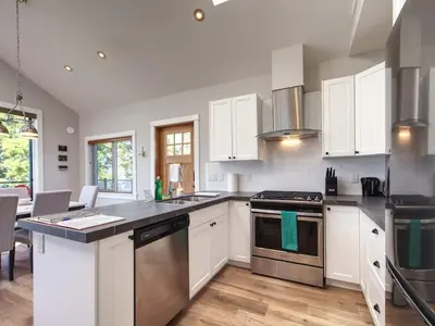 a kitchen with white cabinets and stainless steel appliances at Oceanfront & Amazing Views - Pet Friendly - 2bdrm in Port Renfrew