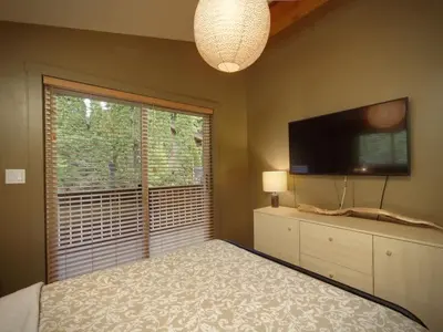 a bedroom with a bed and a tv and a window at The Rocky Knoll - Garden View - Pet Friendly in Port Renfrew